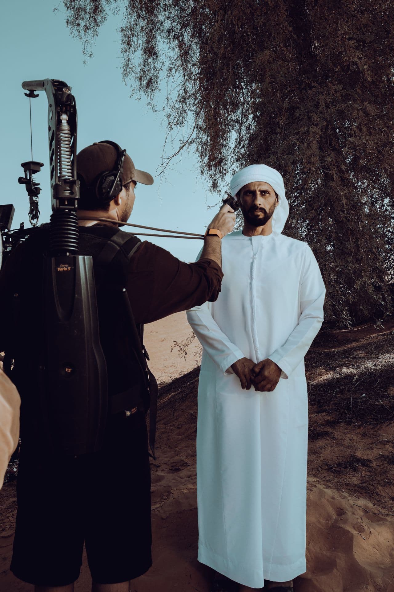 A man in a white kandura between the crew