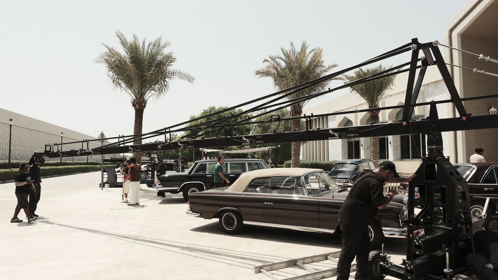 A camera crane over classic cars and palm trees