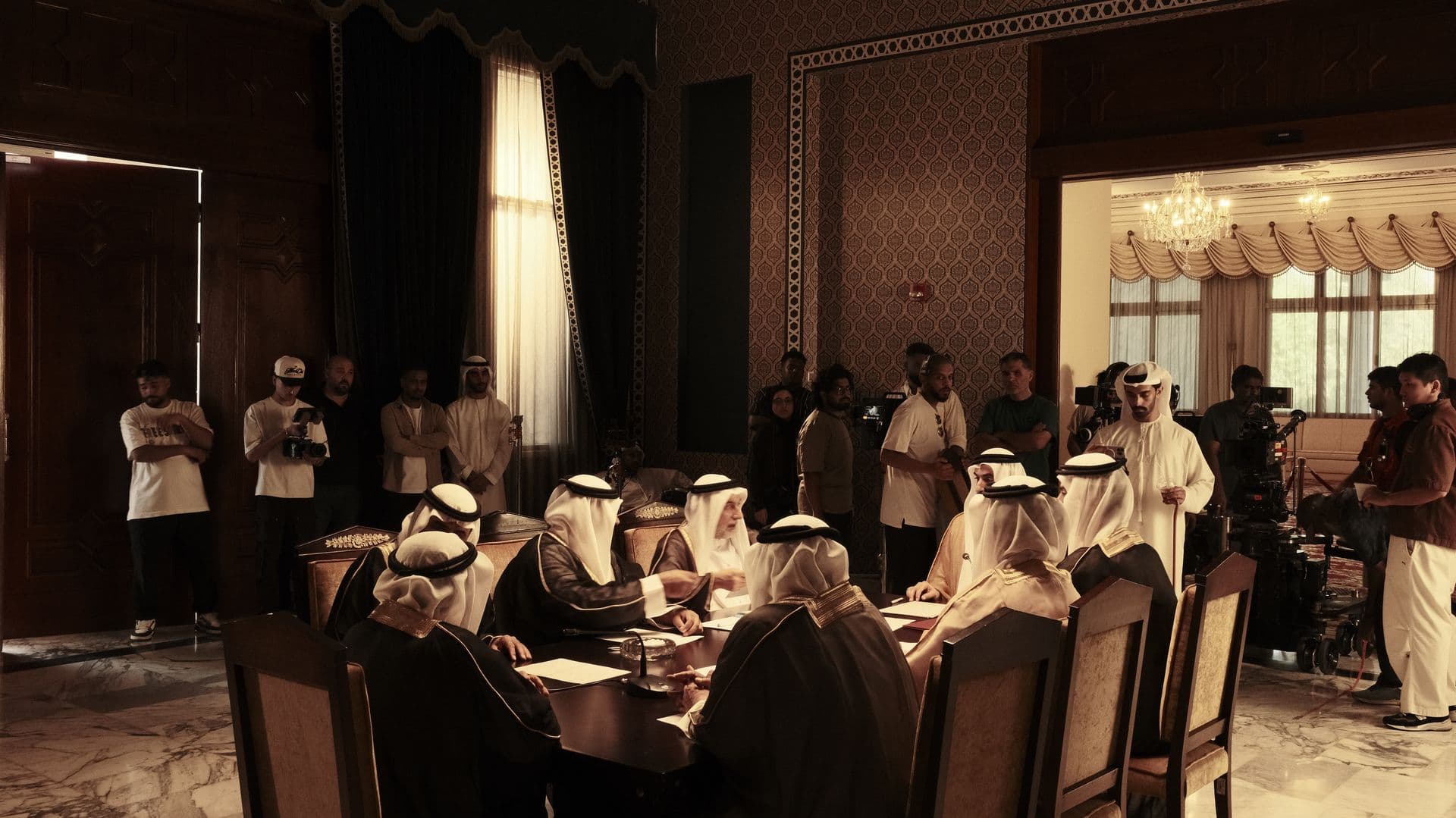 The same room from wide, with crew and lights visible
